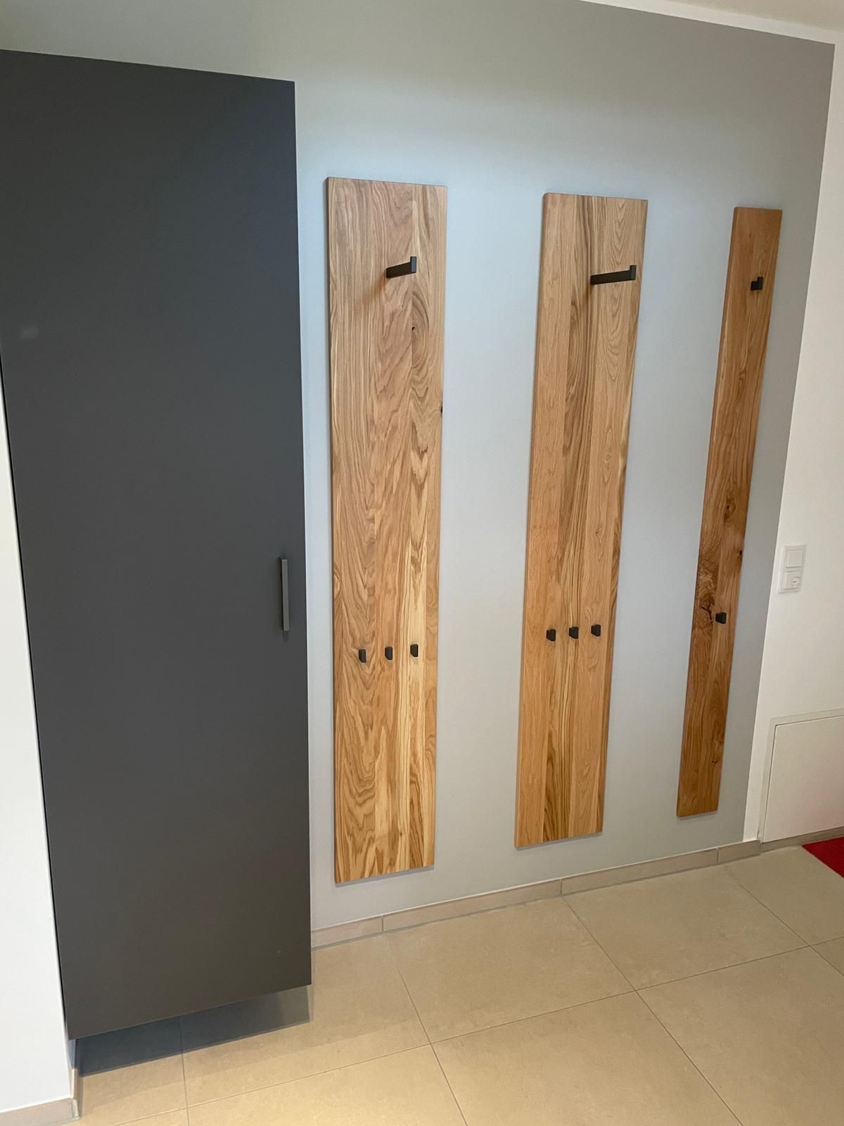 Ein Raum mit einer grauen Tür und Holzhaken an der Wand.