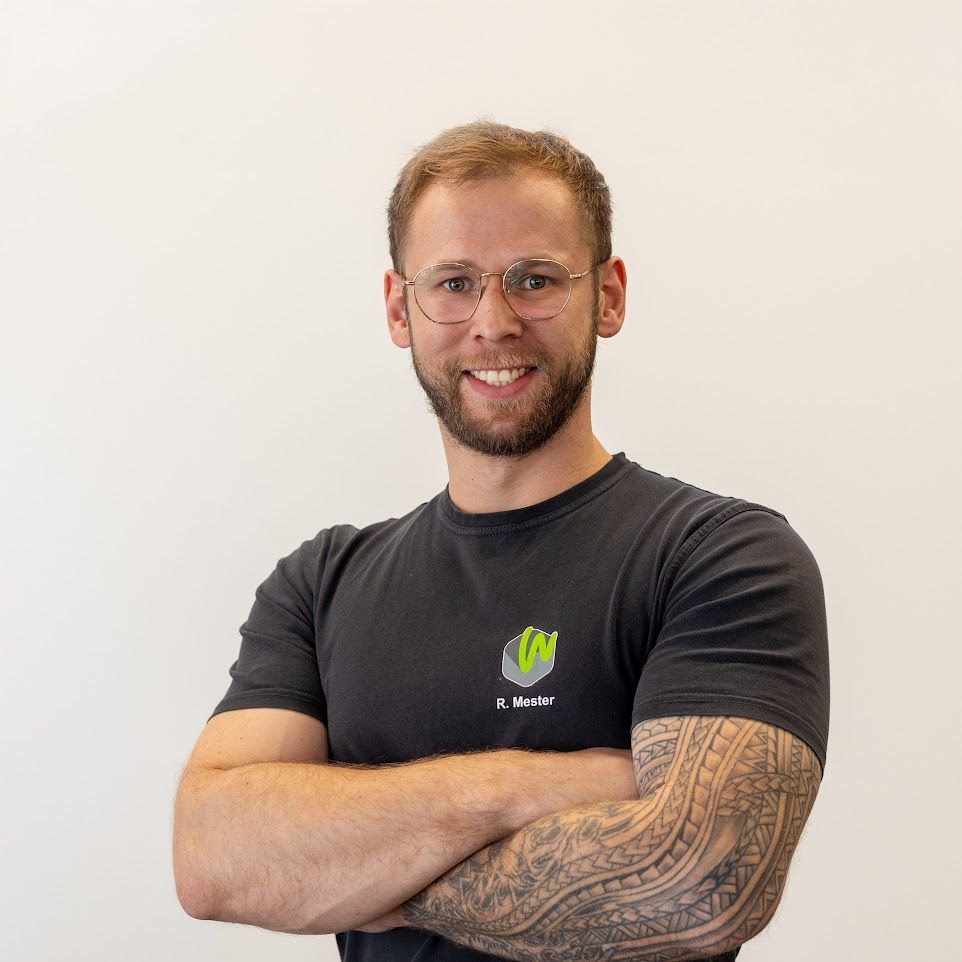Ein Mann mit einer Tätowierung auf dem Arm trägt ein schwarzes T-Shirt.