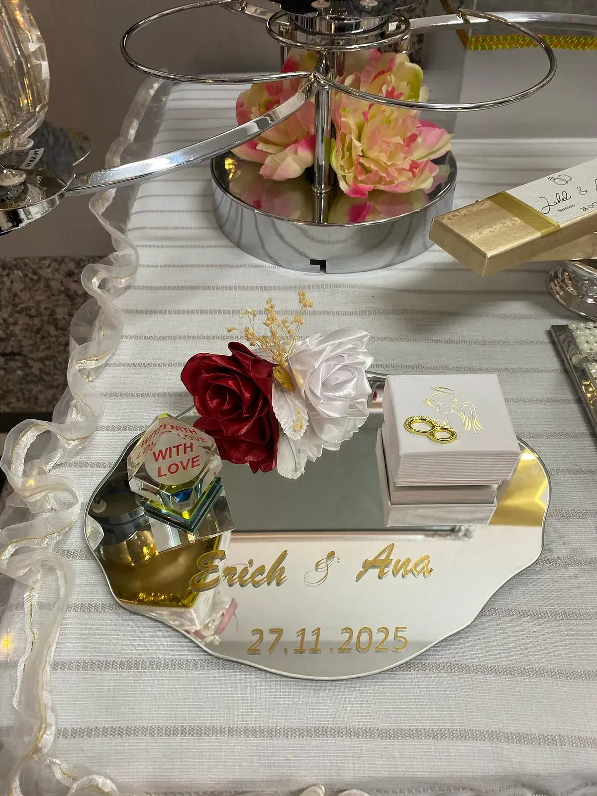 Un espejo con flores y anillos está sobre una mesa.