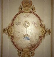 Pintura oval no teto com raios de sol, querubins e moldura dourada ornamentada.