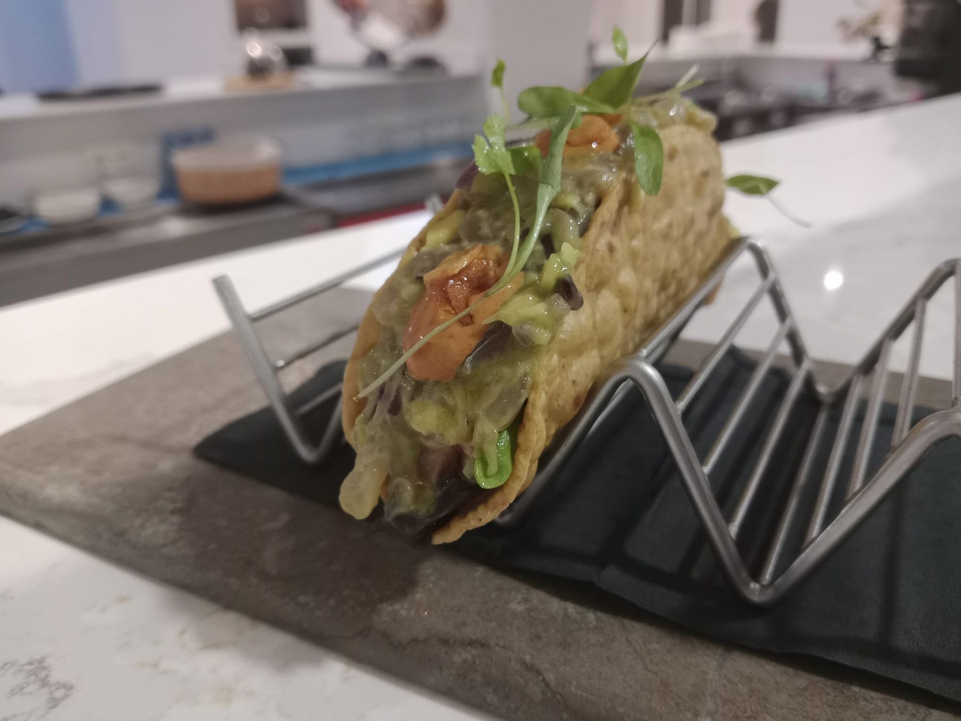 Un taco está sentado en un soporte de metal sobre una mesa.