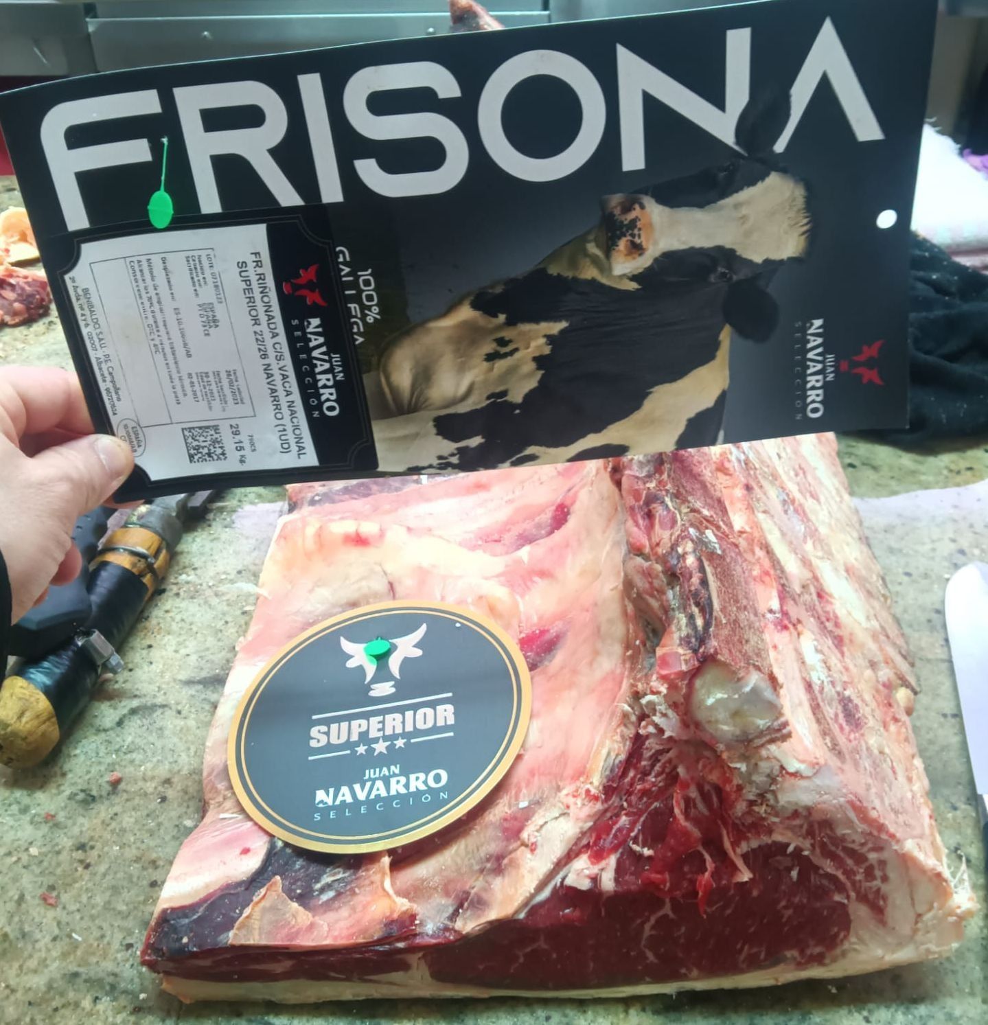 Una persona sostiene una etiqueta de frisona sobre un trozo de carne.
