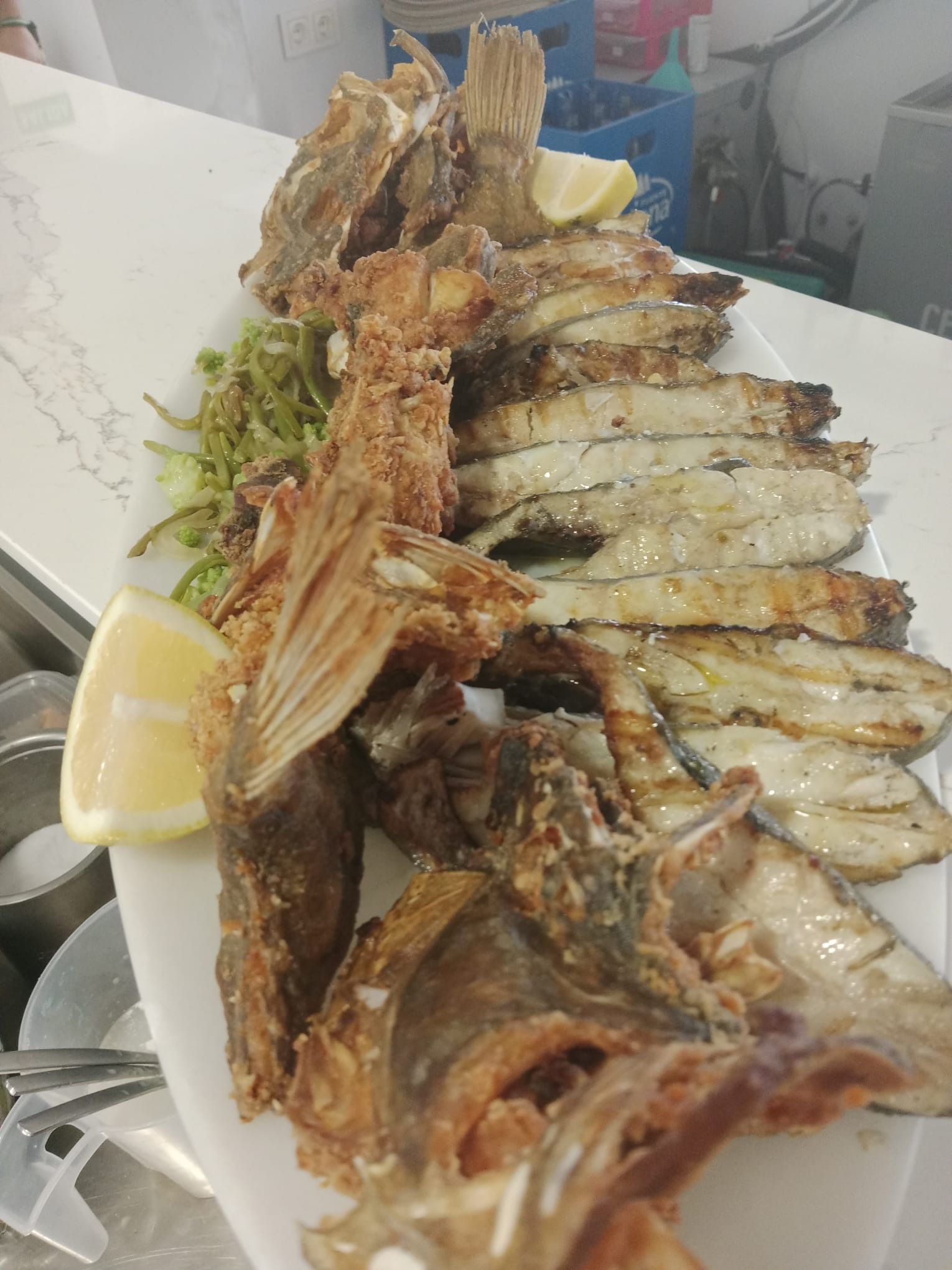 Un plato blanco cubierto con pescado frito y rodajas de limón.