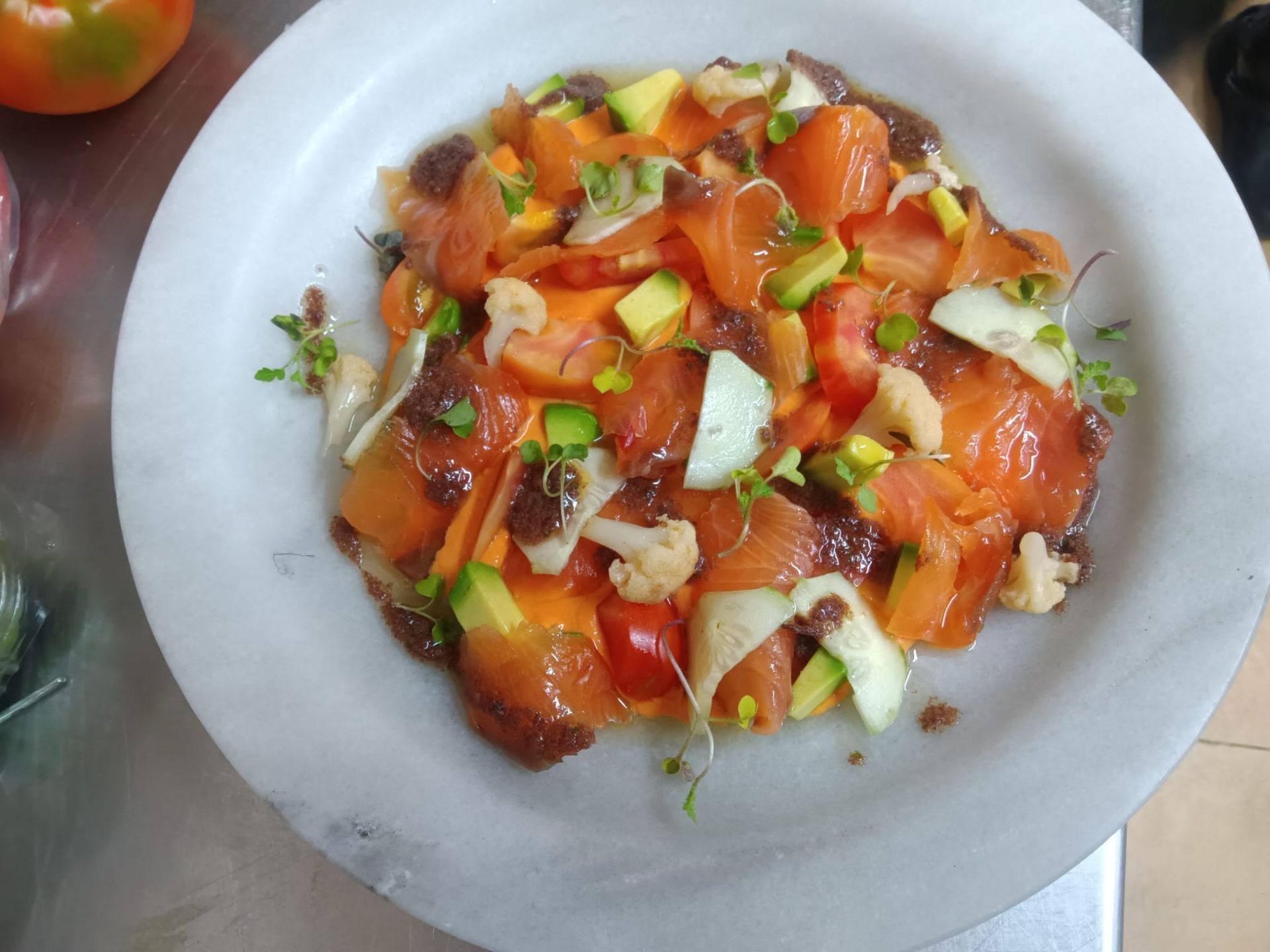 Un plato blanco cubierto con una ensalada de tomates y otras verduras.