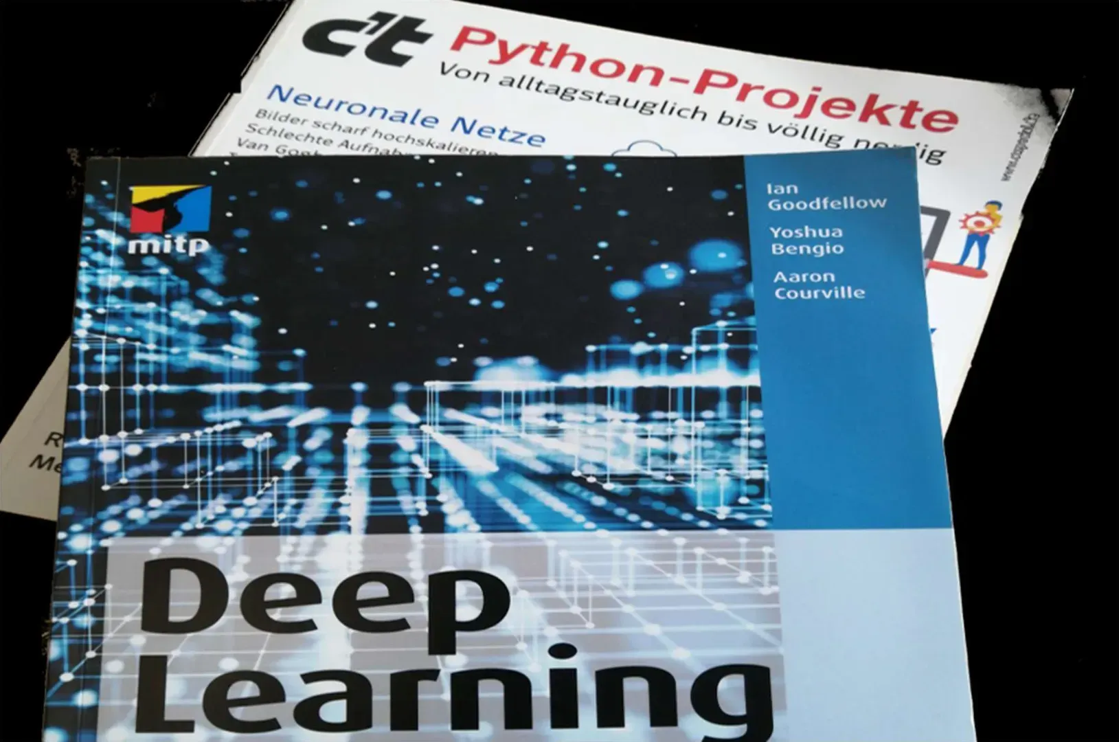 Stapelweise deutsche Zeitschriften über Python-Projekte und Deep Learning, mit blau-weißen Tech-Coverillustrationen.