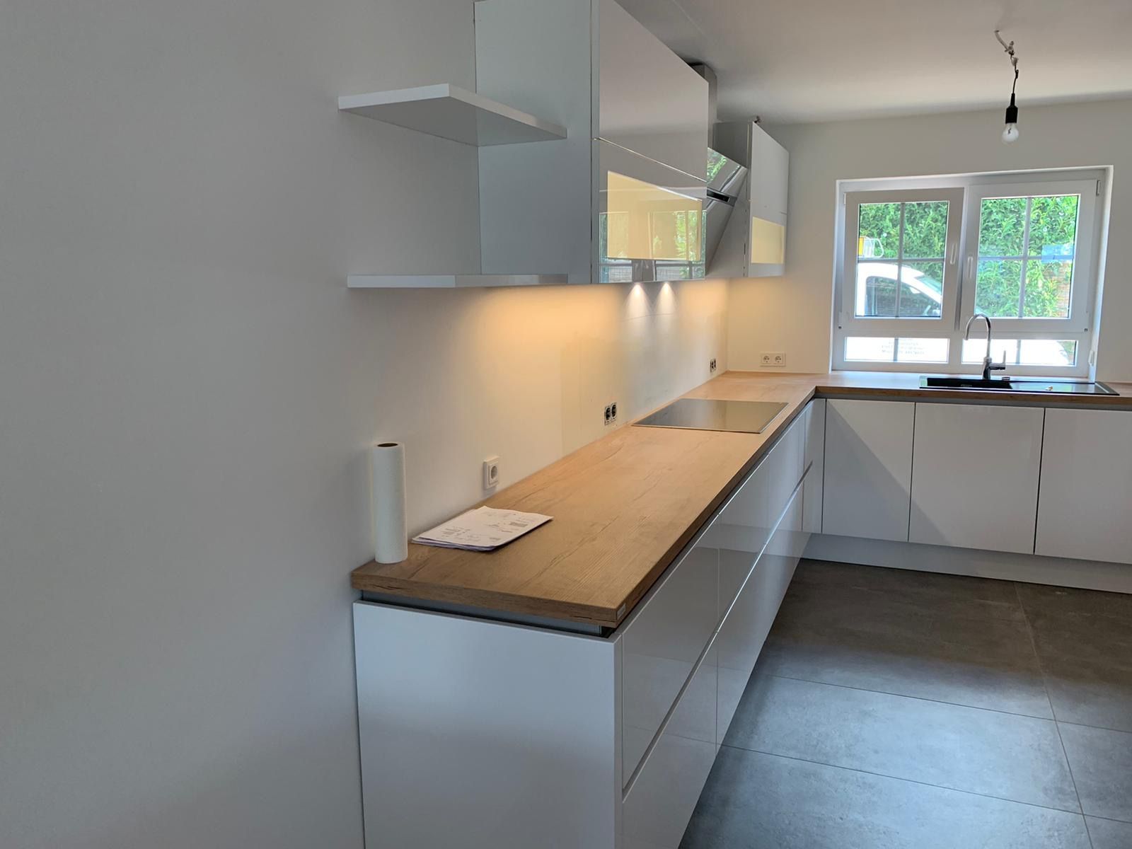 Eine Küche mit weißen Schränken und einer Arbeitsplatte aus Holz.