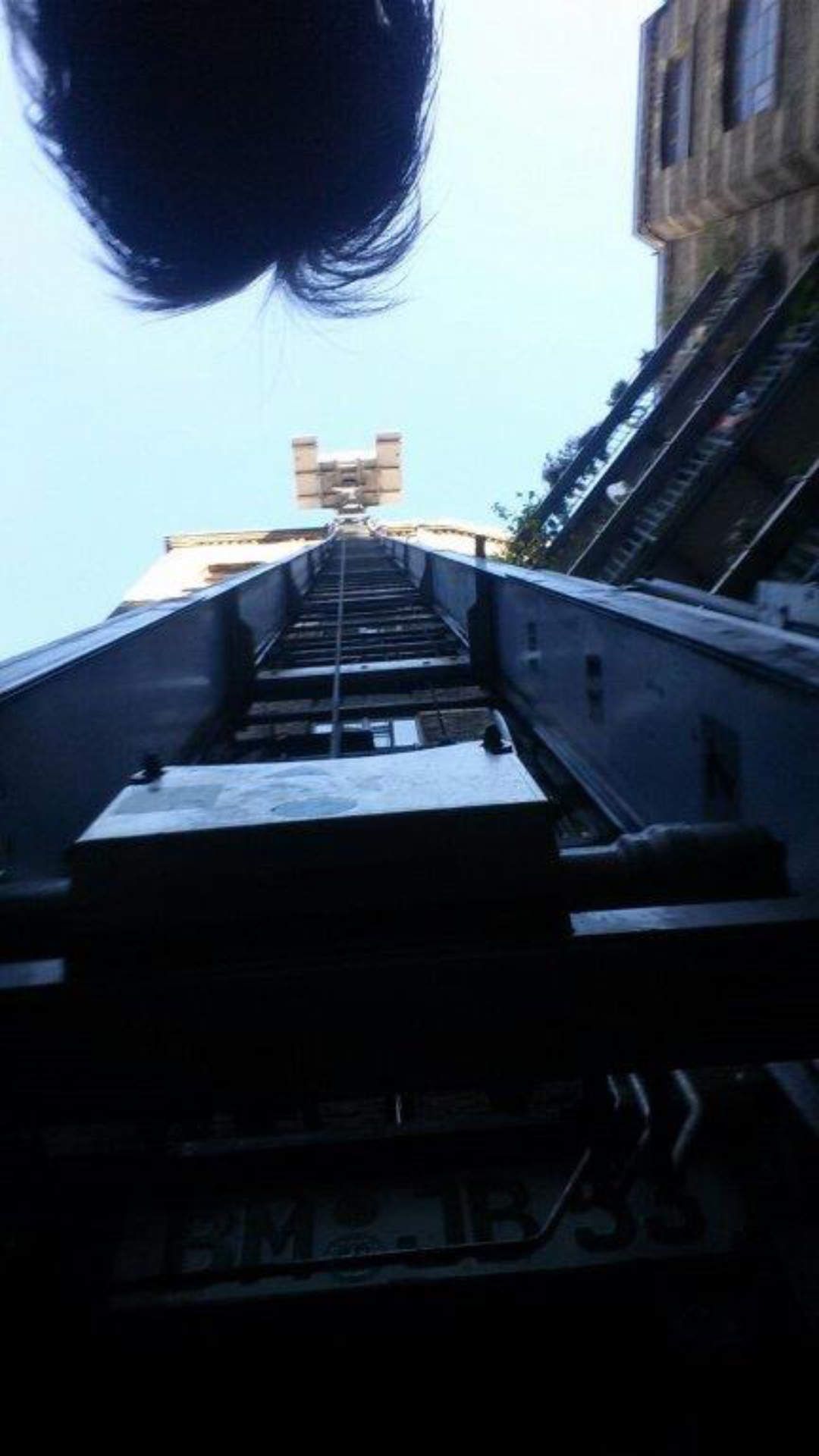 Eine Person blickt zu einer Treppe hinauf, auf der ein Schild mit der Aufschrift „Aufzug“ steht