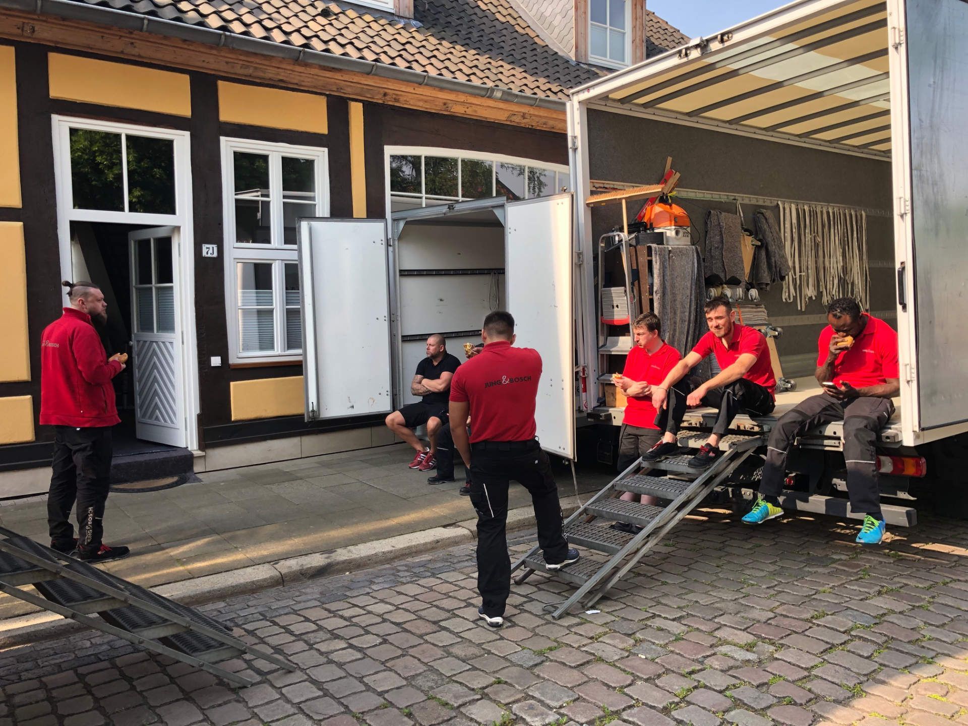 Eine Gruppe Männer sitzt auf den Stufen eines Lastwagens.