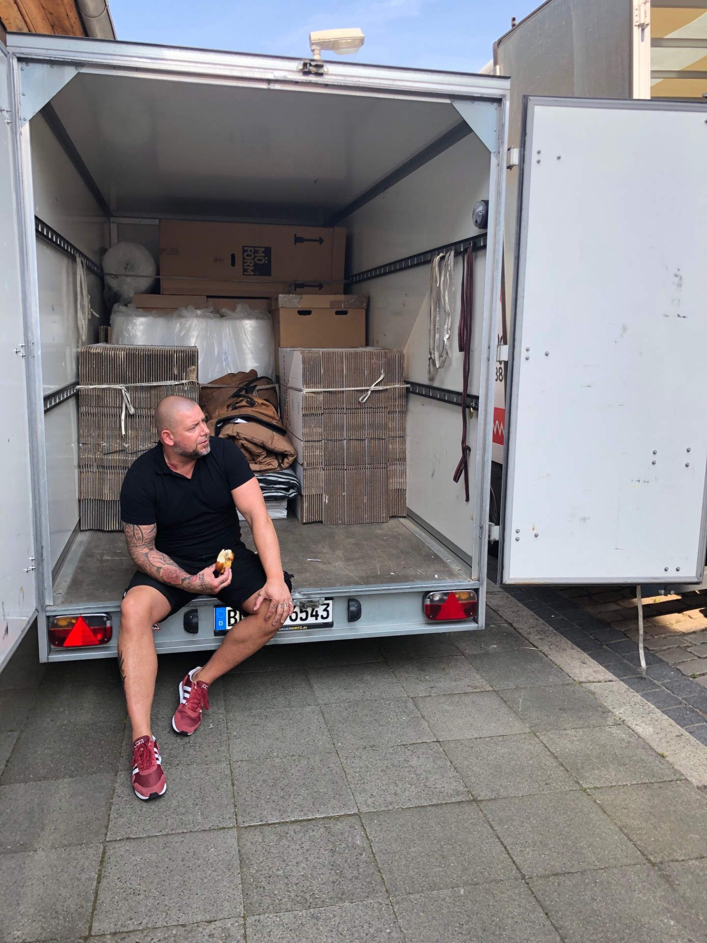 Ein Mann sitzt hinten in einem Anhänger.