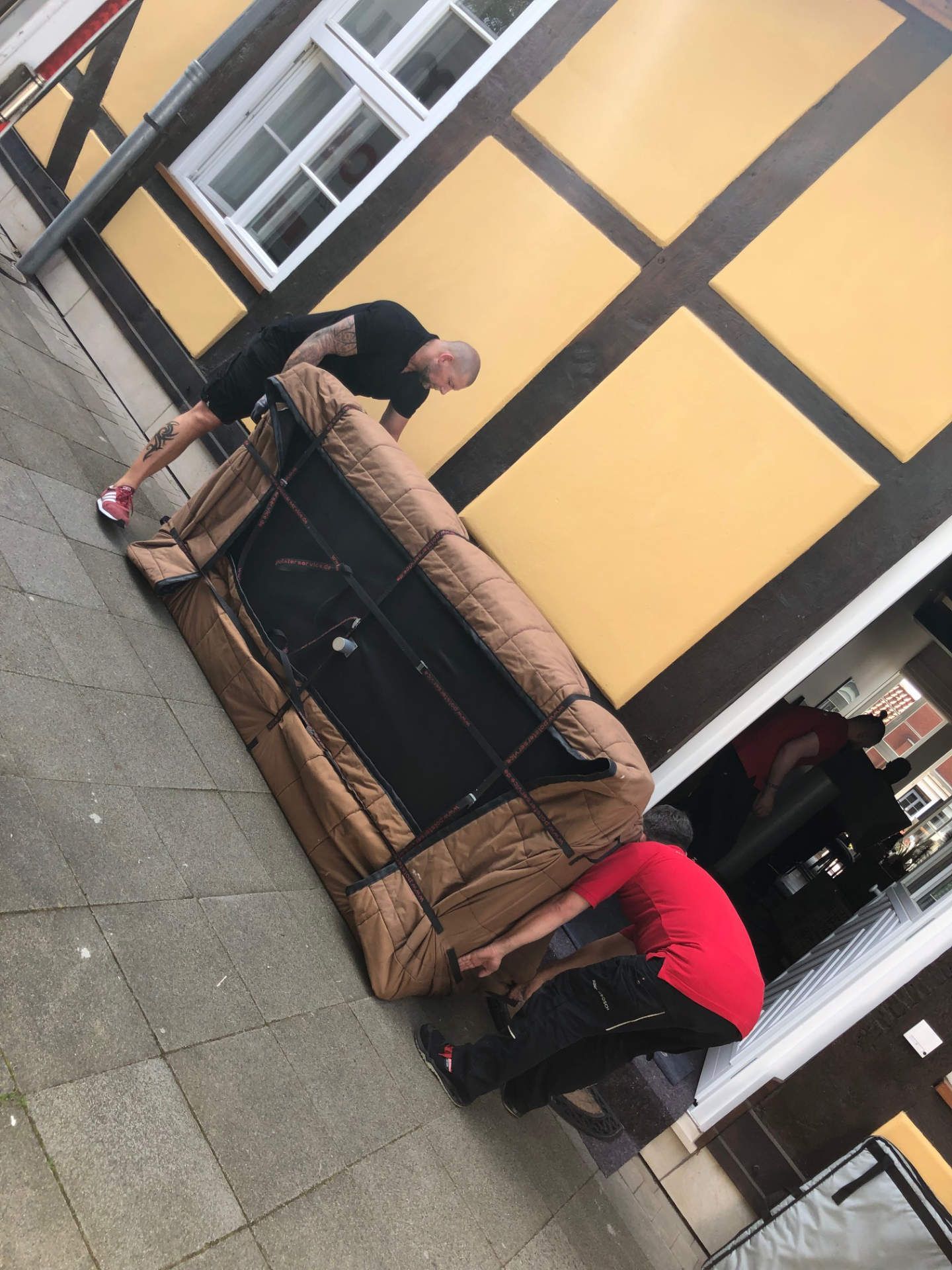 Eine Gruppe von Männern bewegt ein großes Sofa auf einem Bürgersteig
