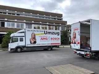 Zwei Umzugswagen stehen vor einem Gebäude.