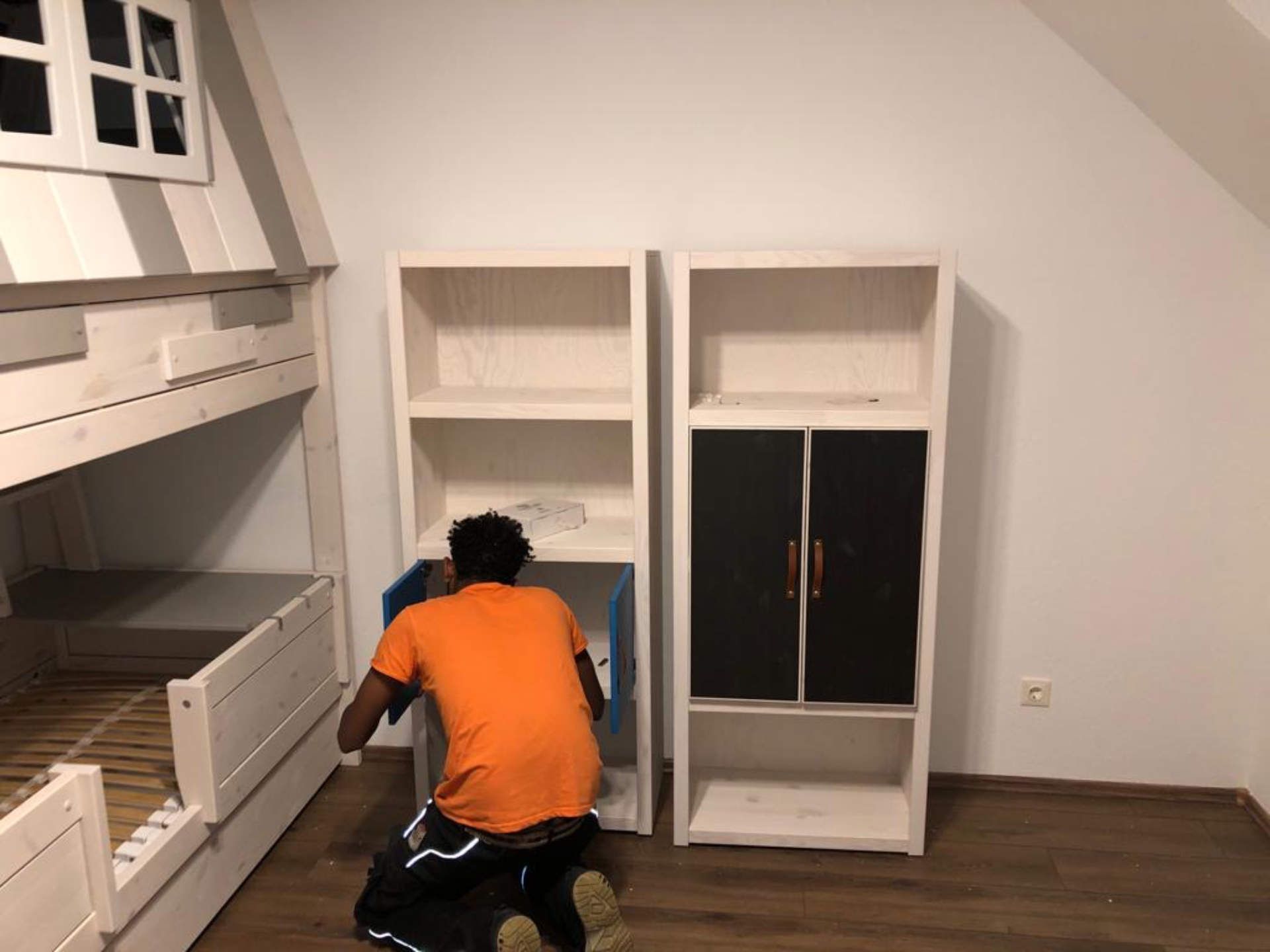 Ein Mann in einem orangefarbenen Hemd arbeitet an einem Etagenbett