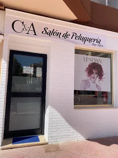 Exterior del salón con puerta y ventana con marco negro. Letrero 