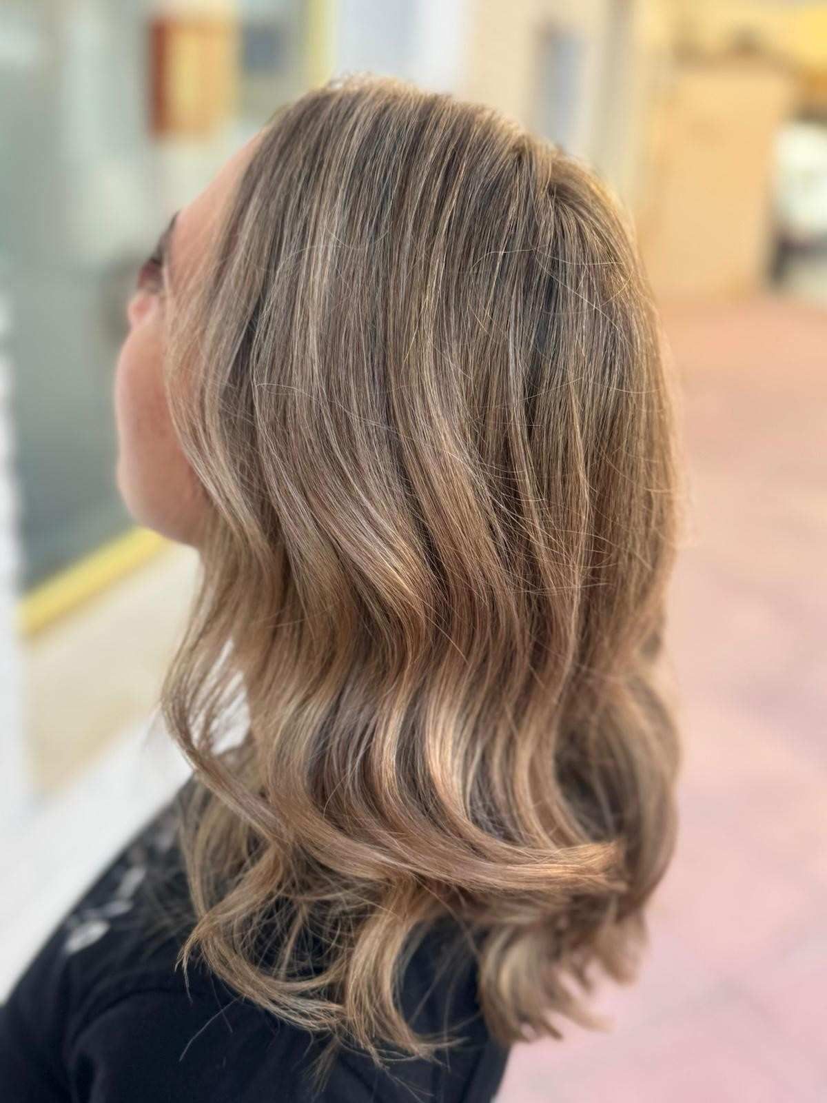 Cabello castaño ondulado y con reflejos de mujer. Mechones castaños claros y oscuros aportan textura y dimensión.