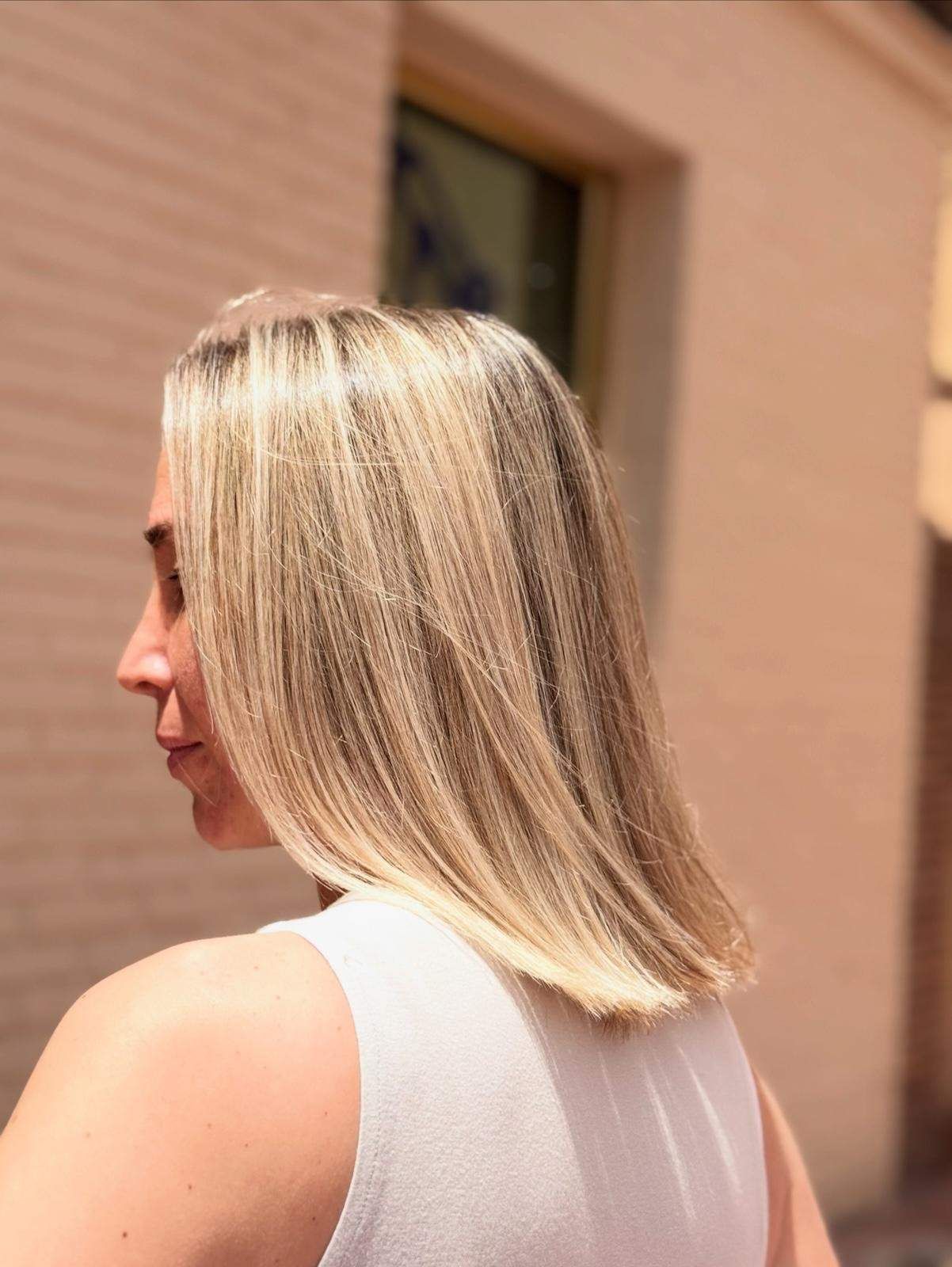 Mujer de cabello rubio y liso, la luz del sol ilumina su perfil.