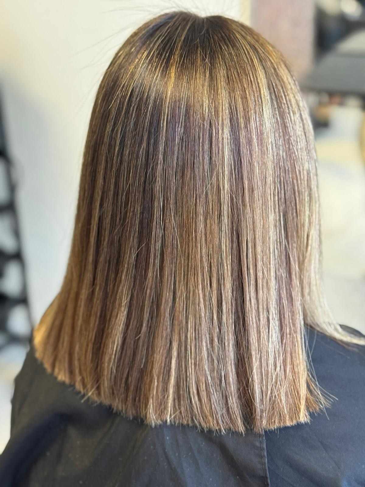 Cabello liso hasta los hombros, con reflejos castaños y rubios. Vista posterior, en interiores.