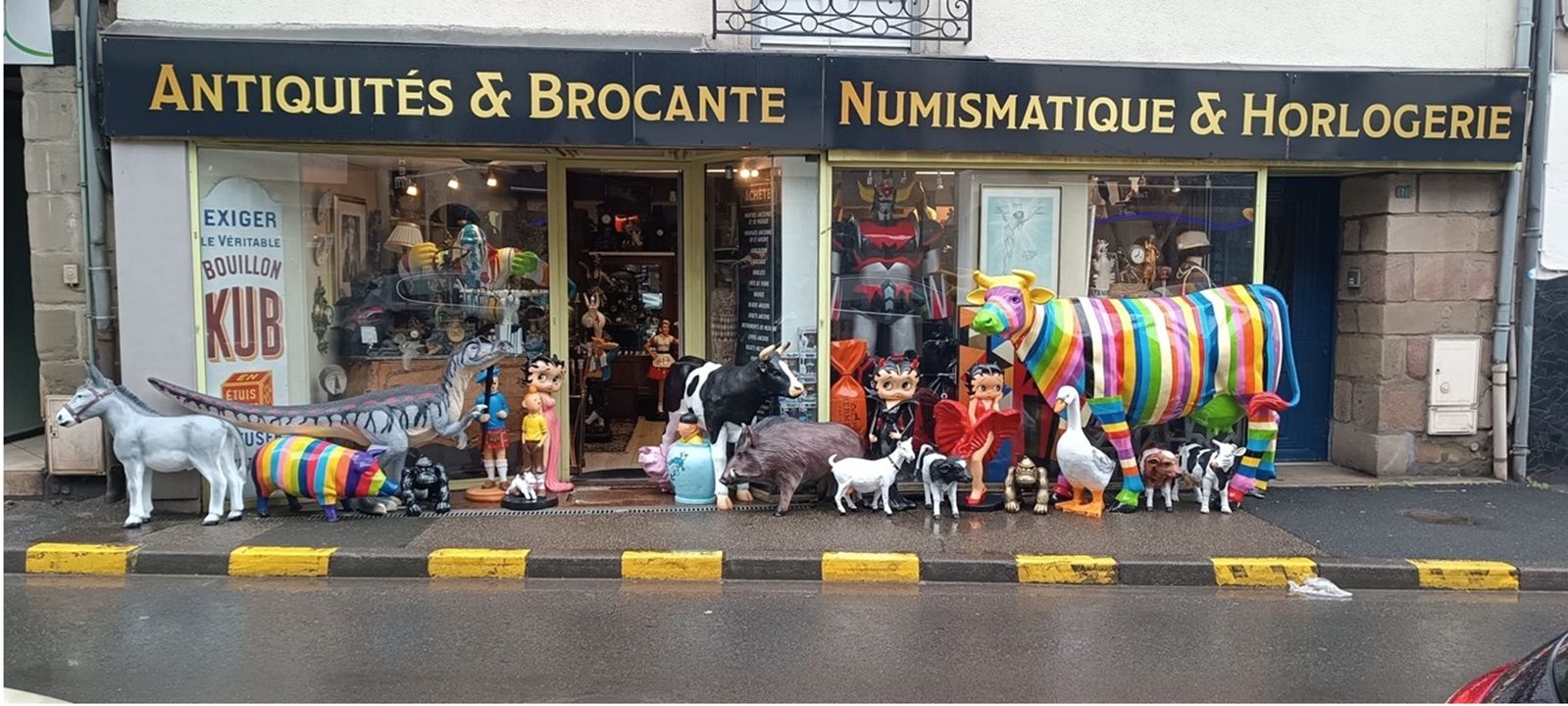 La façade d'un magasin est ornée de diverses sculptures d'animaux sur le trottoir devant celui-ci.