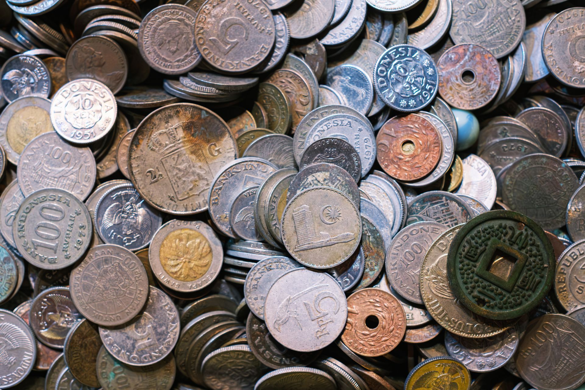 Tas de pièces de monnaie usées et assorties, de tailles et de couleurs variées.