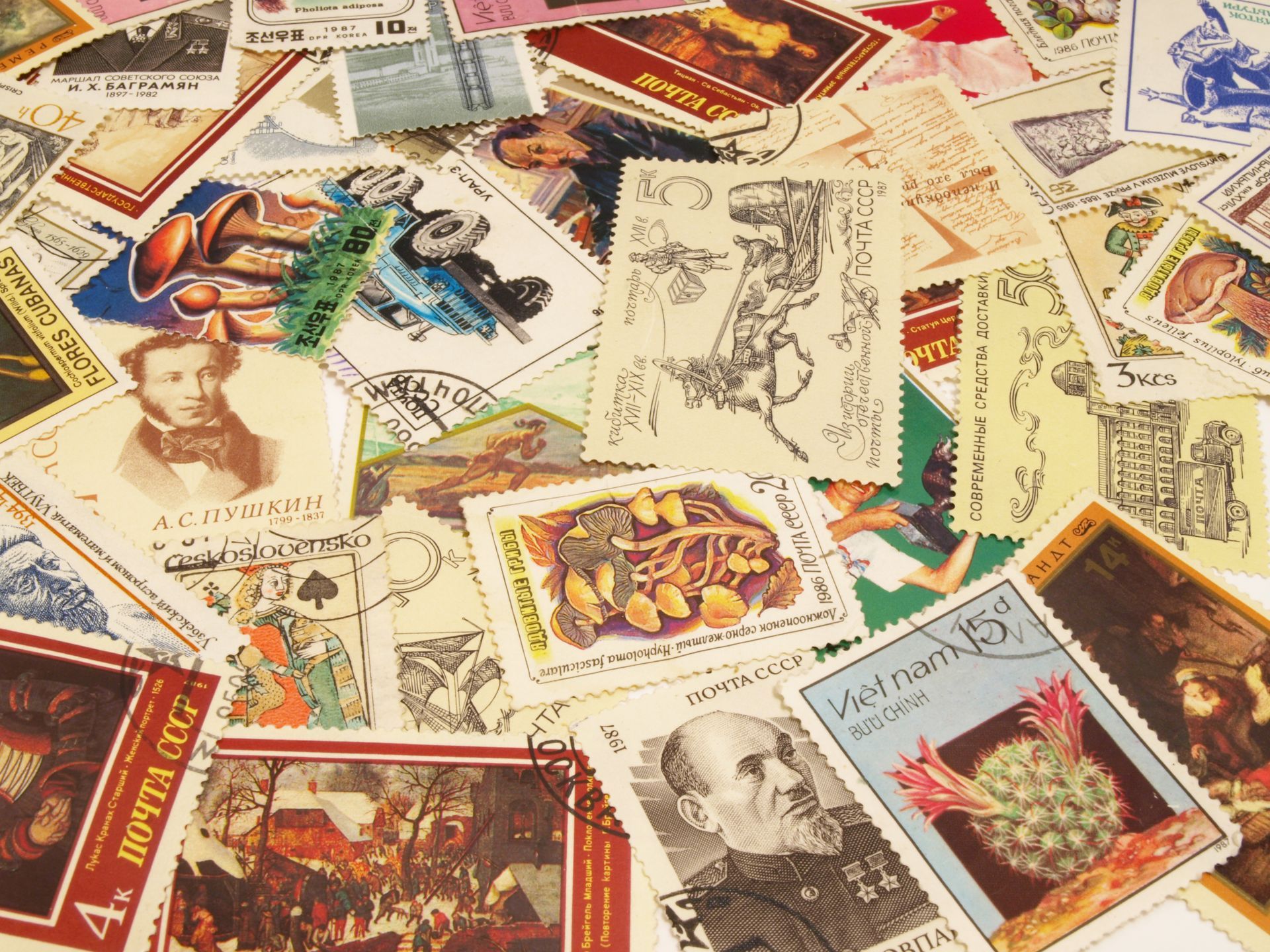 Pile de timbres colorés aux motifs variés, comprenant des portraits, des paysages et des illustrations.