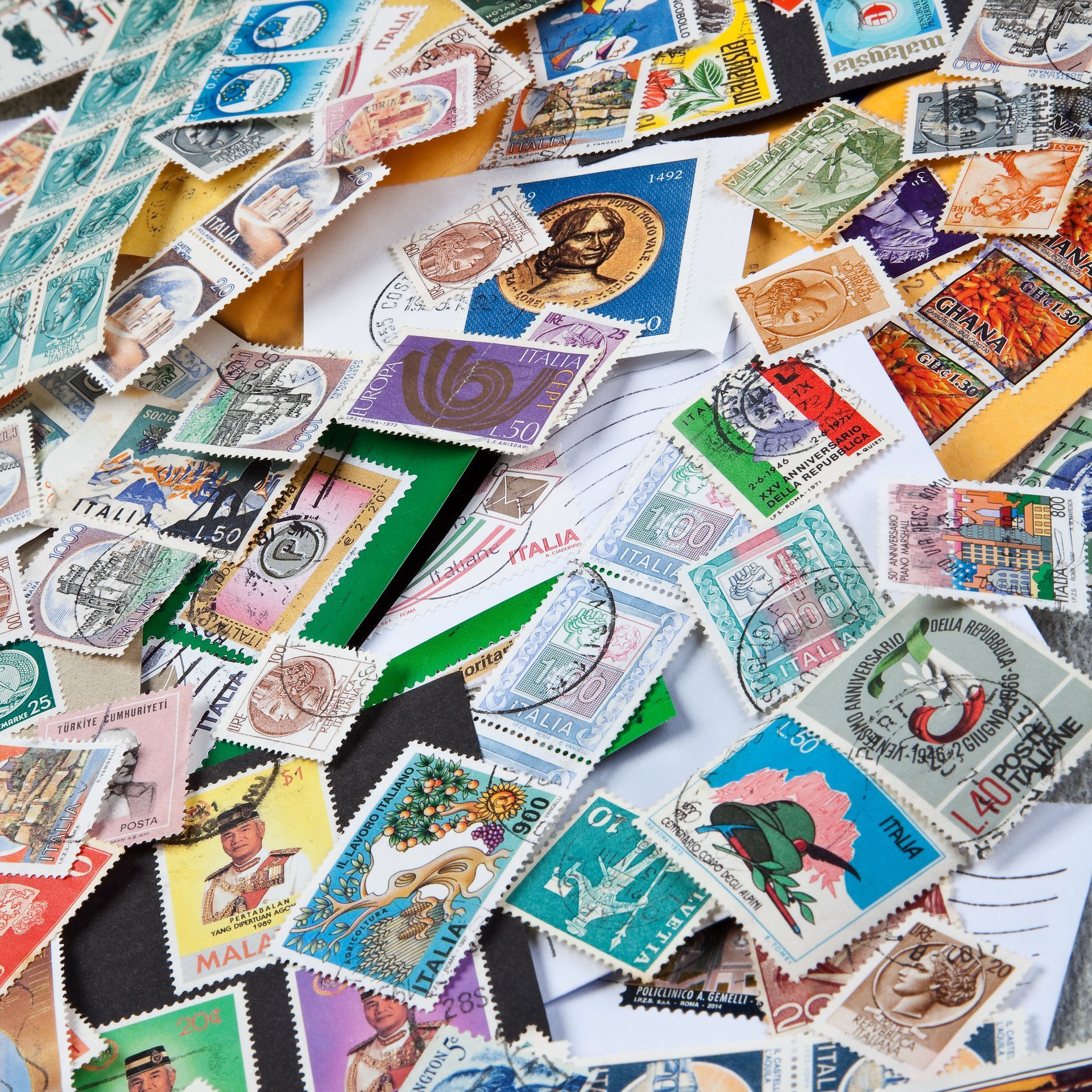 Un tas de timbres-poste colorés, de tailles et de motifs variés, éparpillés sur une surface.