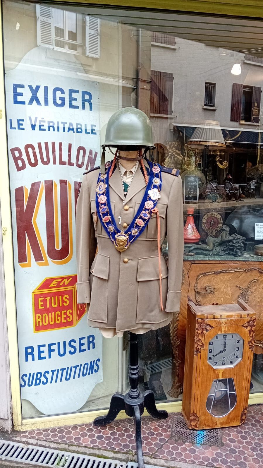 Mannequin en uniforme militaire, casque et médailles compris, dans une vitrine. Panneau Bouillon KUB à côté.