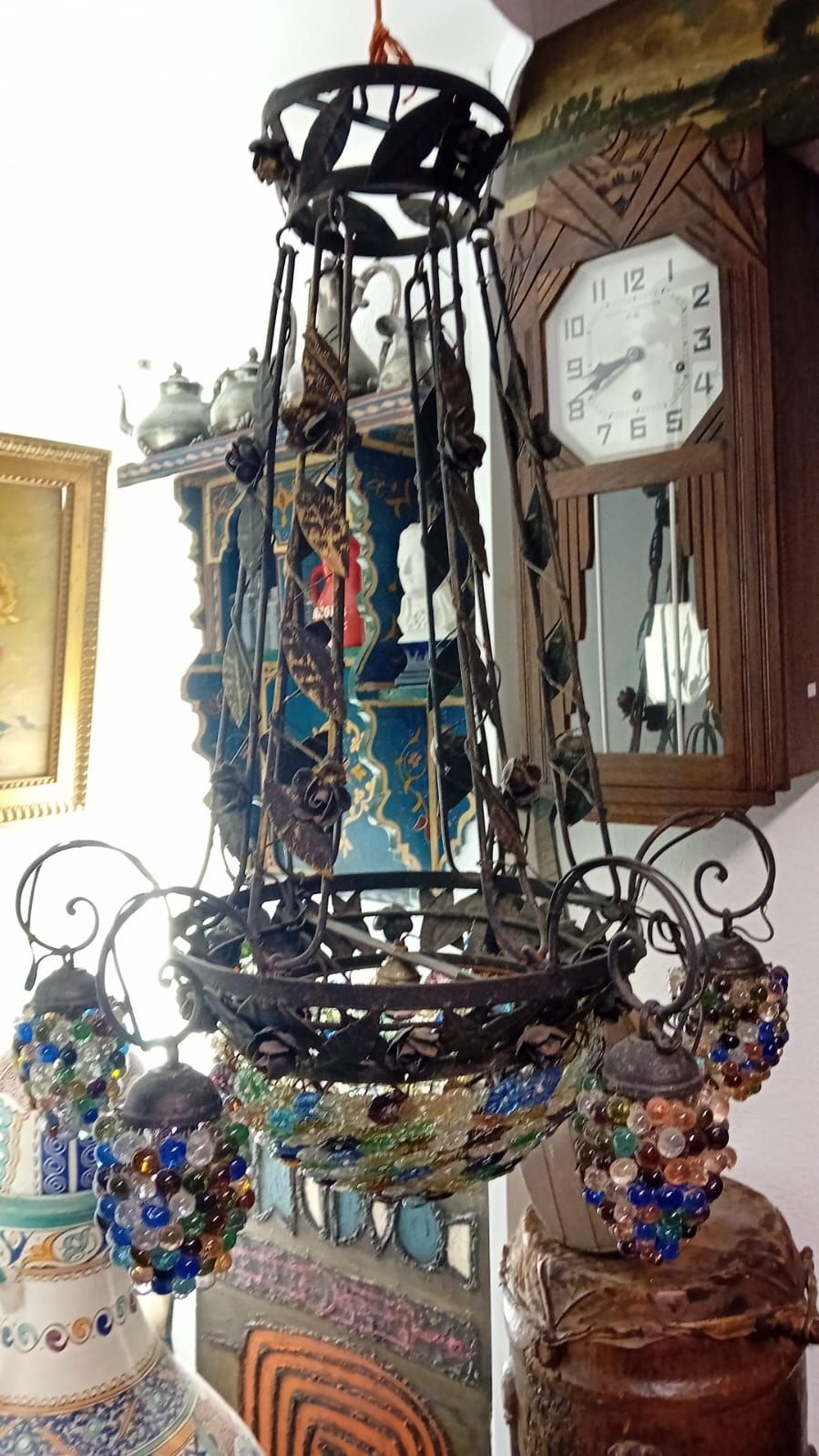 Un lustre orné de globes en perles de verre est suspendu dans une pièce agrémentée d'autres éléments de décoration, notamment une horloge.