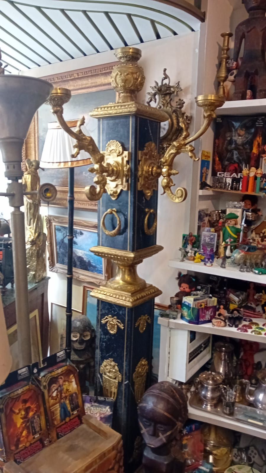 Porte-manteau orné, noir et or, dans une boutique d'antiquités, avec détails décoratifs et crochets.