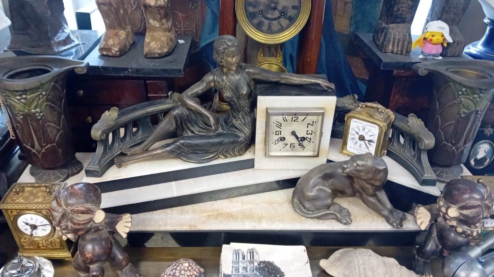 Vitrine présentant un assortiment d'horloges et de sculptures anciennes.