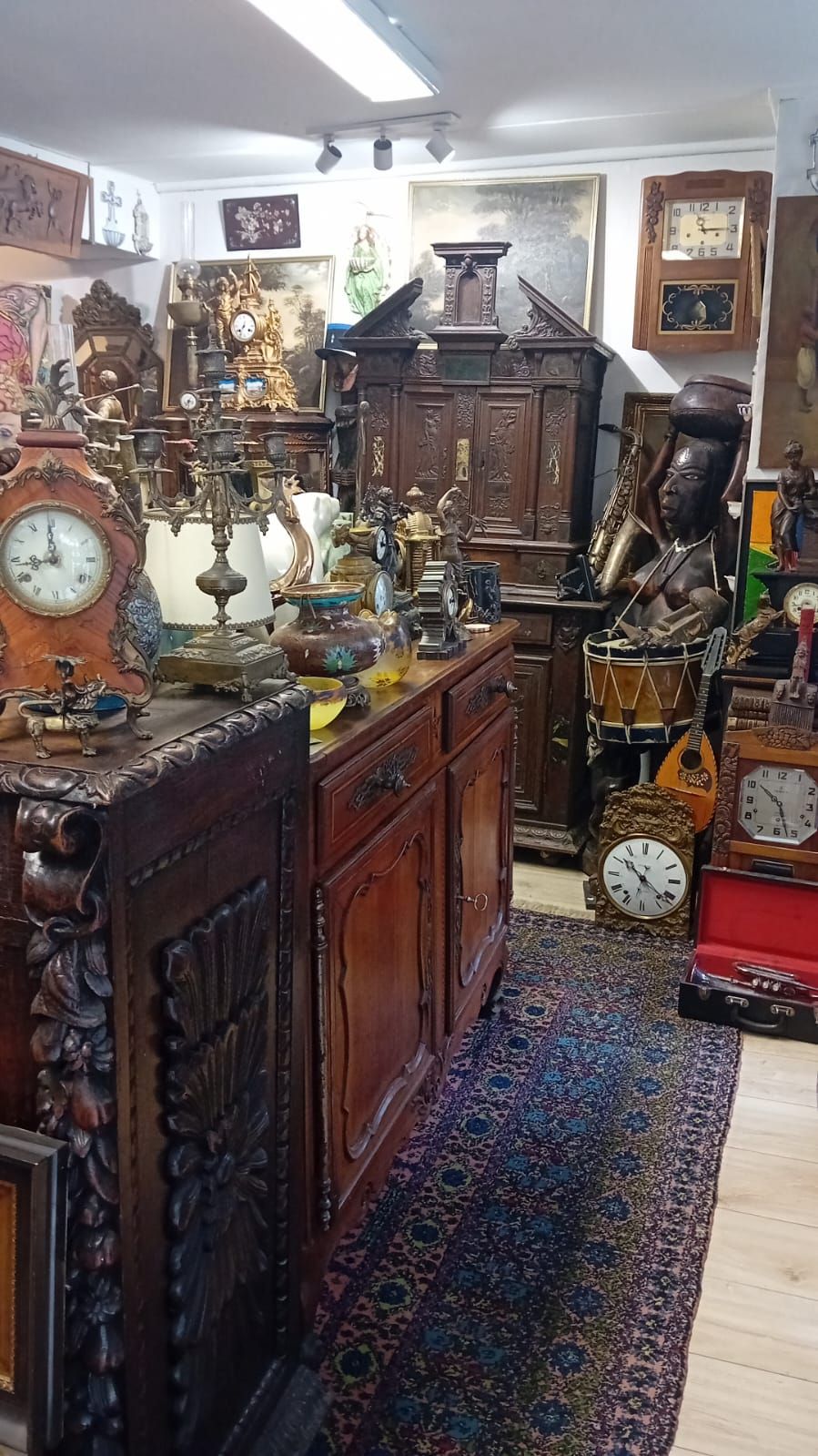 Intérieur d'un magasin d'antiquités rempli d'horloges, de meubles et d'objets vintage divers.
