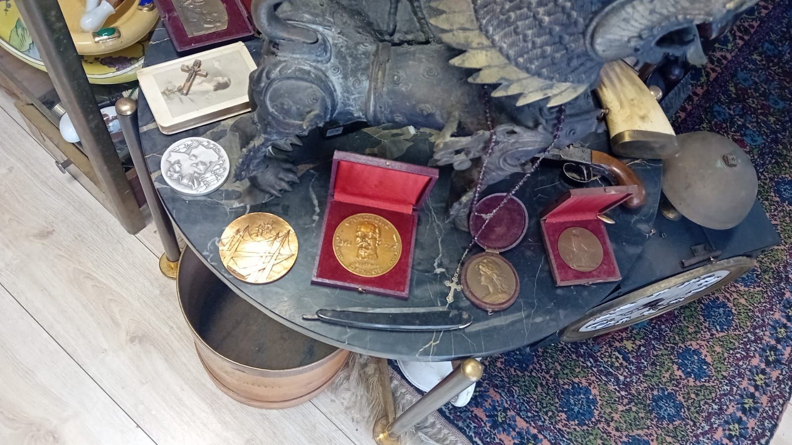 Médailles d'or dans des boîtes rouges, étalage d'objets de collection sur une table en marbre.