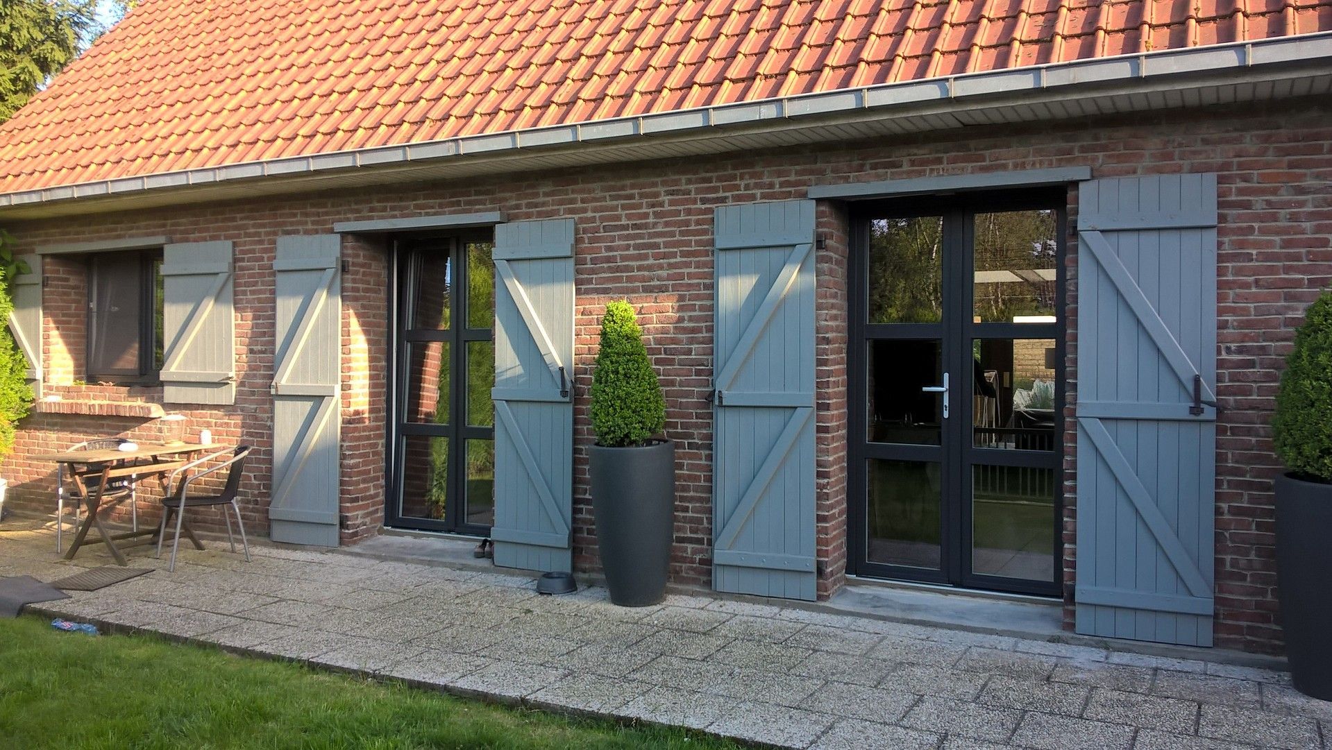Maison en briques avec volets et portes grises