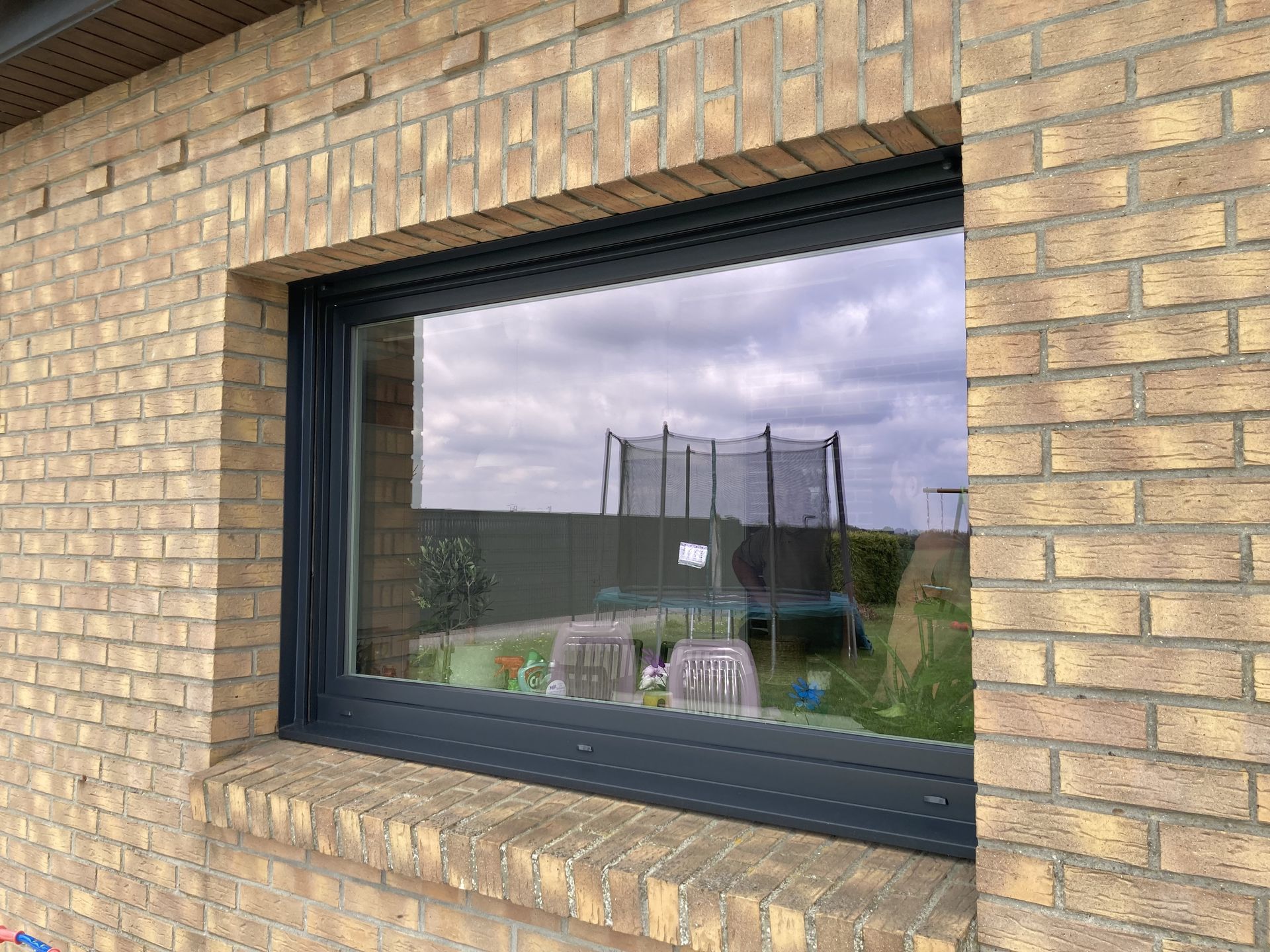 Fenêtre fixe grise d'une façade en briques claires