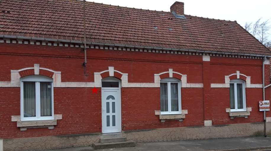 Une maison en briques rouges avec des menuiseries blanches