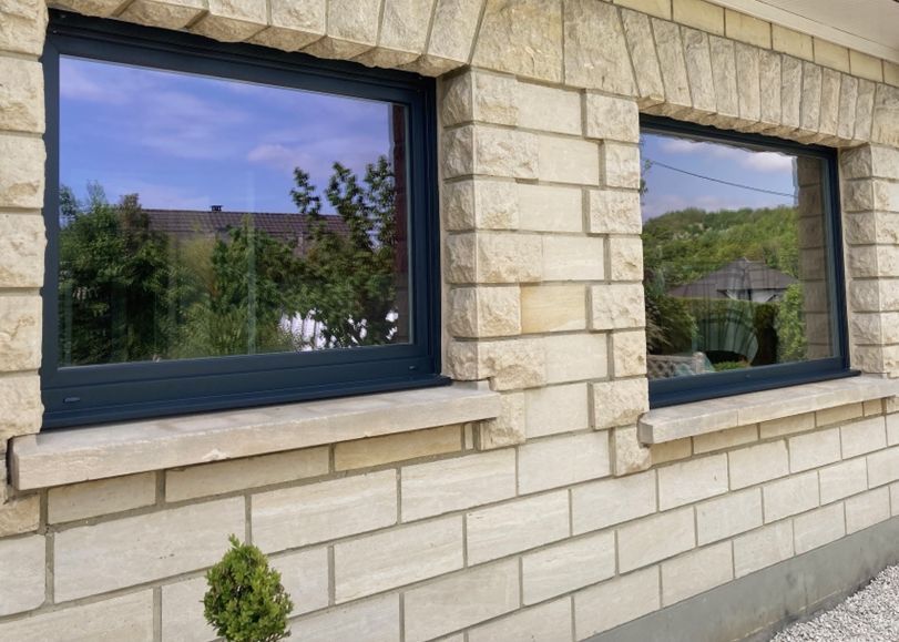 Une façade en pierres avec des fenêtres en aluminium