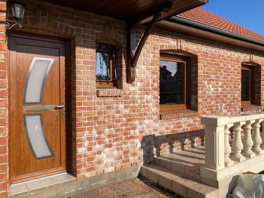 Une façade en brique avec une porte vitrée en bois