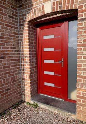 Une porte d'entrée rouge d'une façade en briques