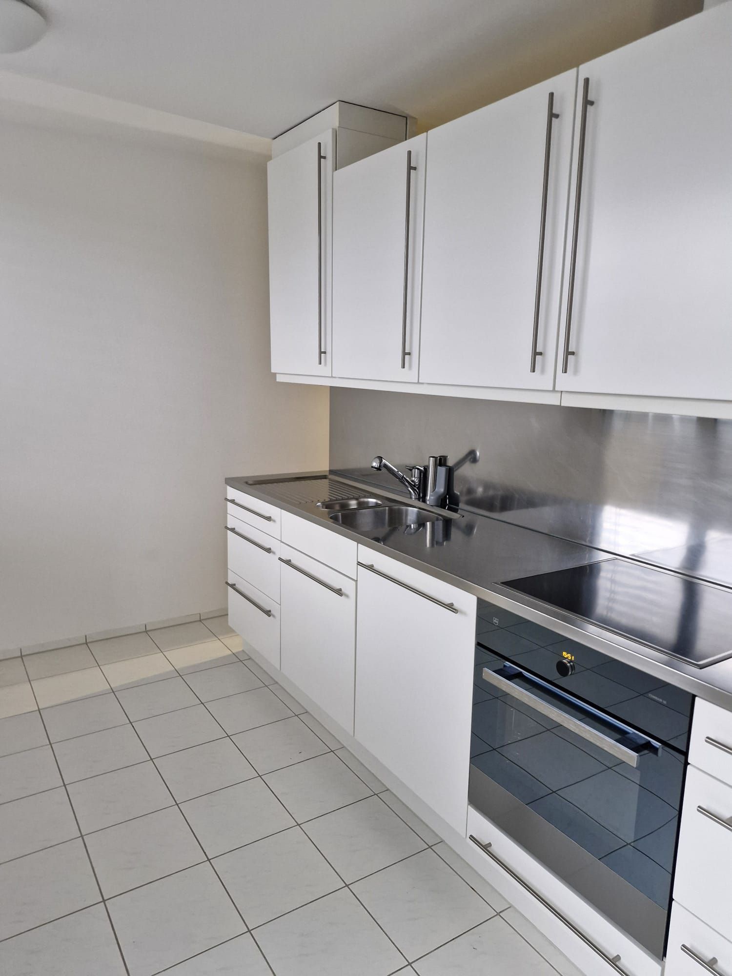 Helles Wohnzimmer mit Teppichen, Esstisch und grossen Fenstern mit Blick auf einen Garten.