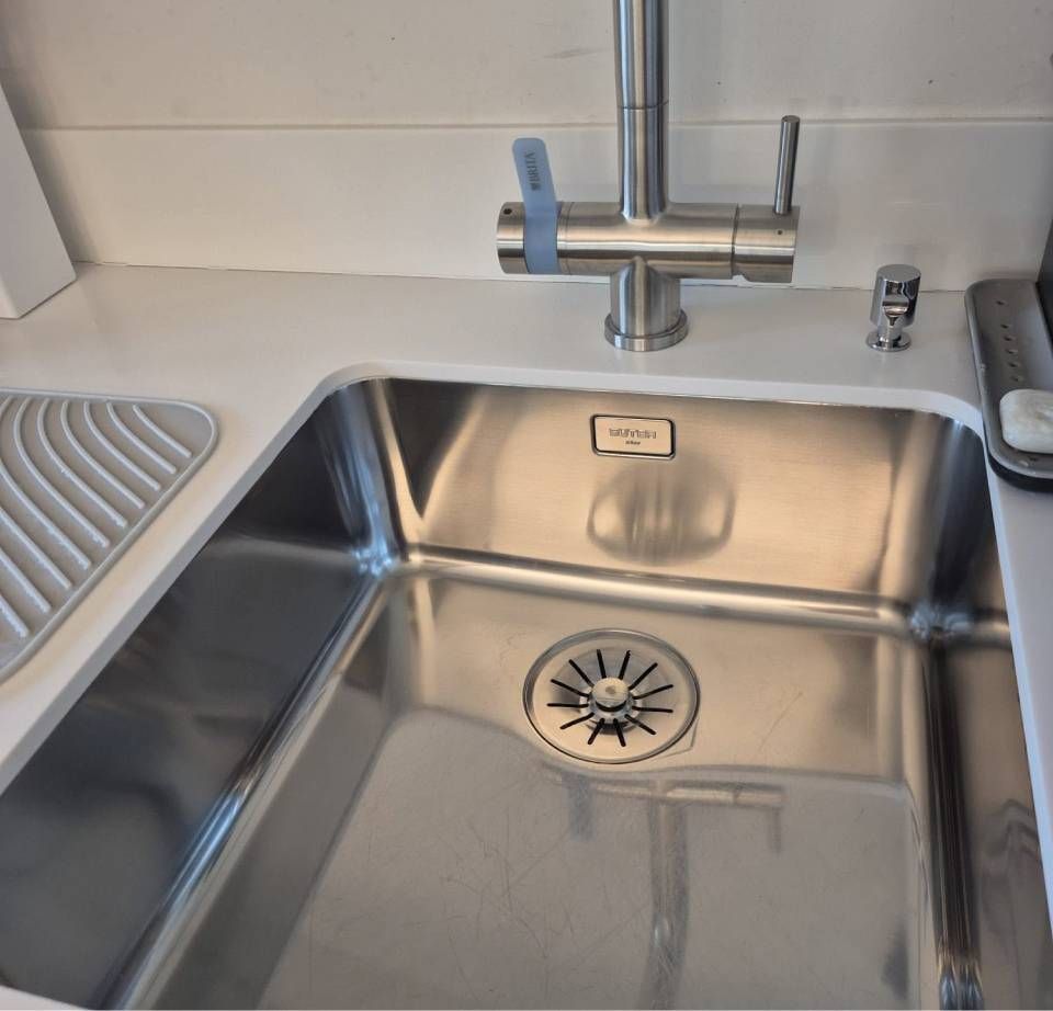 Küchenspüle aus Edelstahl mit Armatur und Zubehör.