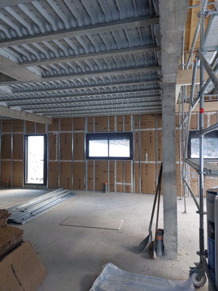 Des mains gantées installent l'isolant entre les montants en bois.