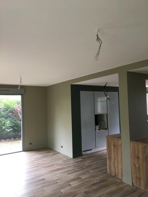 Intérieur avec murs vert, sauge, parquet clair et placards de cuisine blancs.