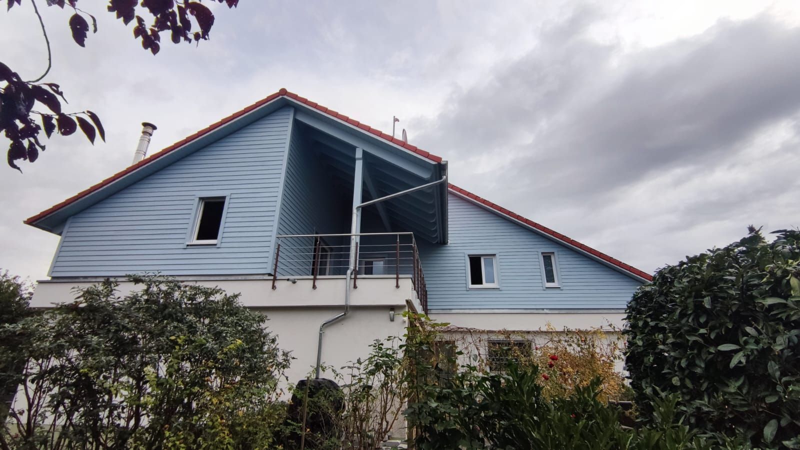 Ein blaues Haus mit einem roten Dach und einem Balkon