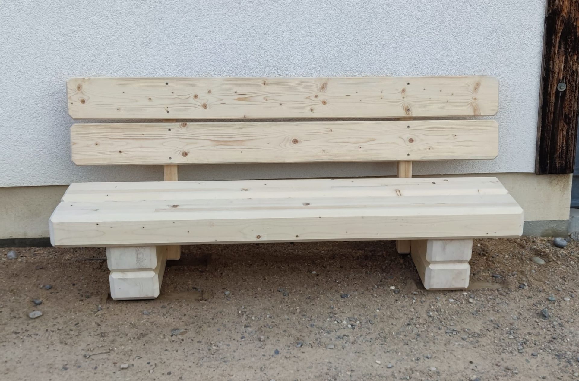 Eine Holzbank steht vor einem Gebäude