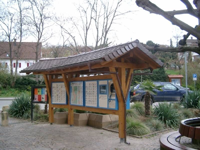 Ein Holzunterstand mit einem davor geparkten blauen Auto