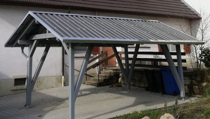 Ein Carport mit Metalldach steht vor einem Haus