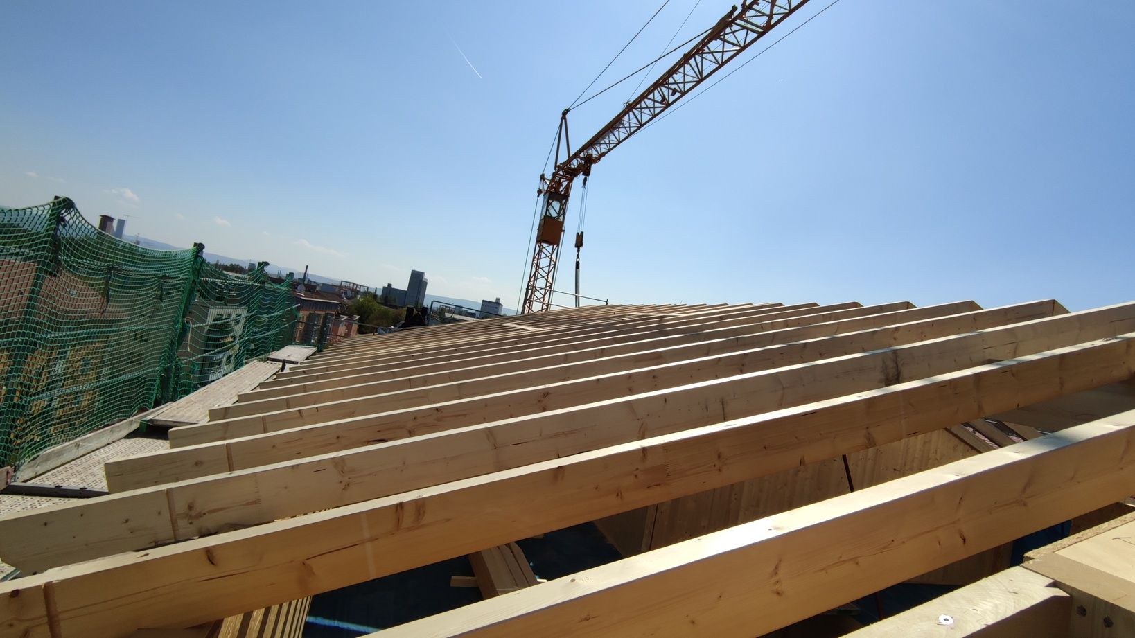 Auf einem Stapel Holzbalken steht ein Kran.