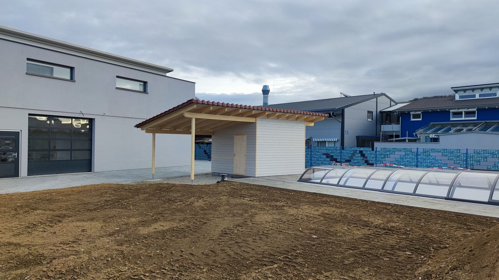 Neben einem Swimmingpool wird ein Haus gebaut.