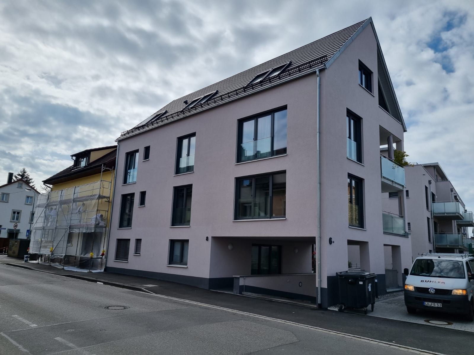 Ein weißer Lieferwagen steht vor einem großen Gebäude