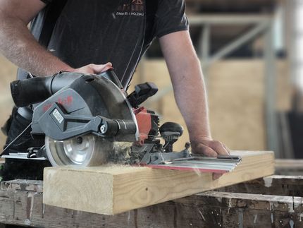 Ein Mann schneidet mit einer Kreissäge ein Stück Holz