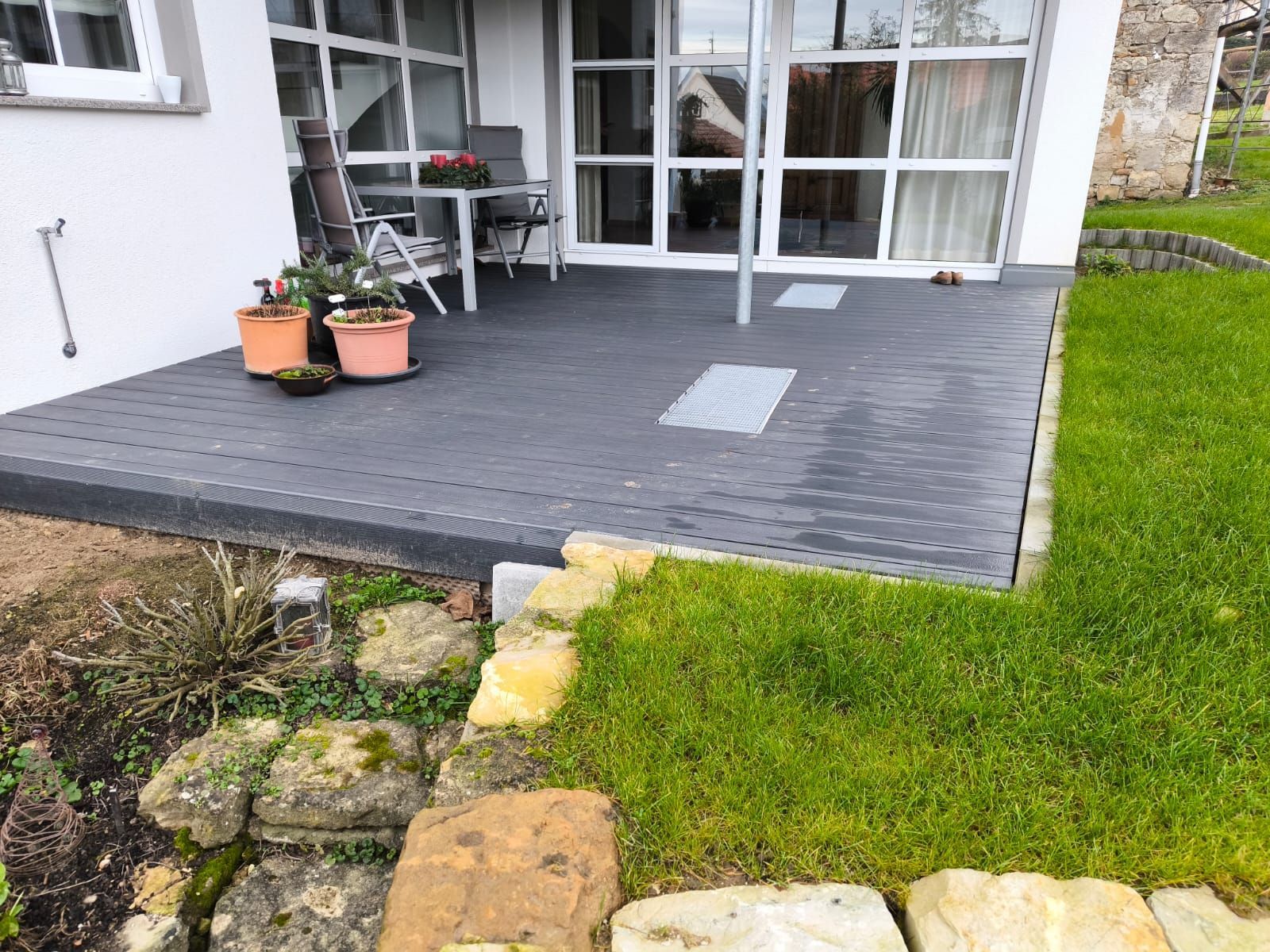 Eine Terrasse mit Topfpflanzen vor einem Haus.