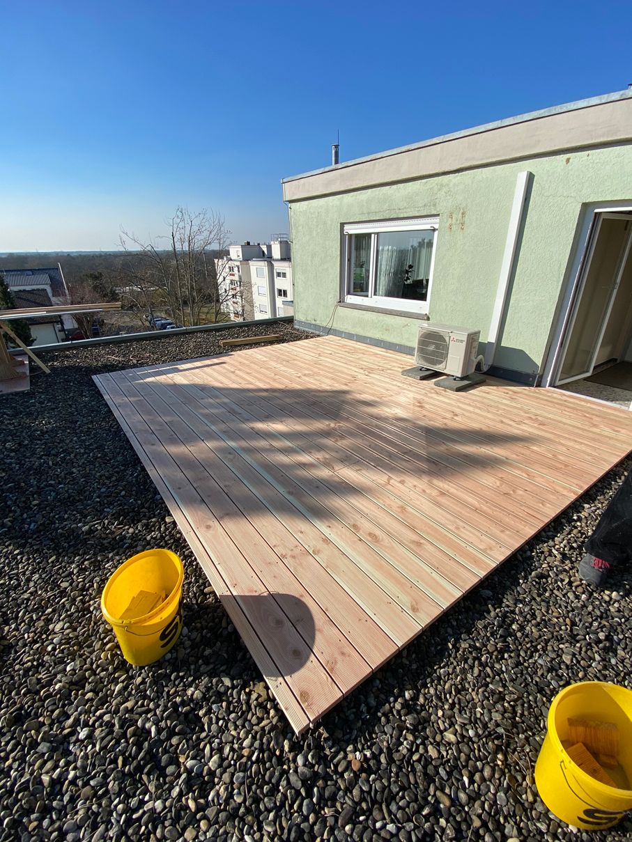 Auf dem Dach eines Gebäudes wird eine Holzterrasse gebaut.